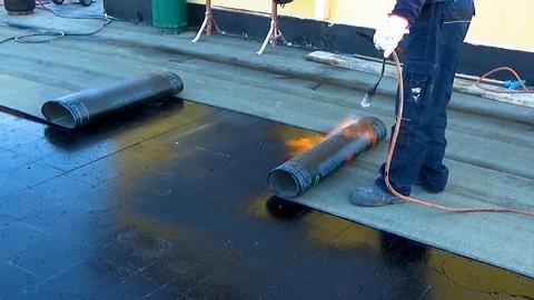 Worker performs sealing overlapping bitumen sheets on the flat roof of the bu 스톡 동영상 99605581
