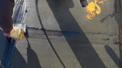 Worker performs sealing overlapping bitumen sheets on the flat roof of the bu 스톡 동영상 99746462