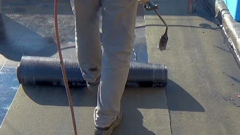 Worker performs sealing overlapping bitumen sheets on the flat roof of the bu 스톡 동영상 99747281
