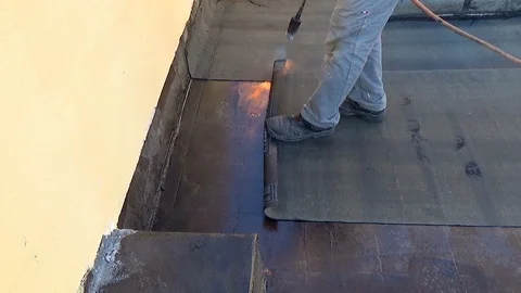 Worker performs sealing overlapping bitumen sheets on the flat roof of the bu Vídeo Stock 99747652
