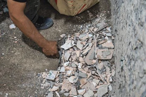 Worker picking up broken ceramic tiles construction material Stock Photos