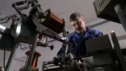 The worker places the coil with copper wire in the winding machine. Electric Video stock 75149052