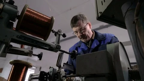 The worker places the coil with copper wire in the winding machine. Electric Video stock 75149187