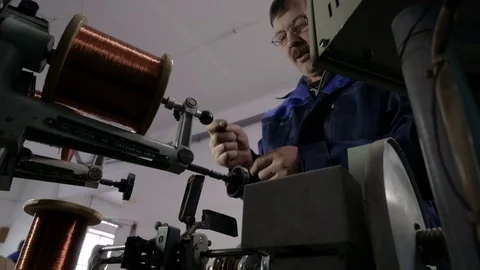 The worker places the coil with copper wire in the winding machine. Electric Video stock 75149722