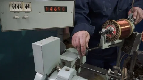 The worker places the coil with copper wire in the winding machine. Electric Video stock 75338395