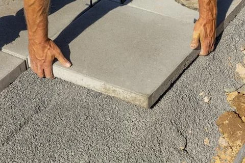 Worker  places the tile exactly at the bed of small paving stones Stock Photos