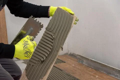 Worker placing ceramic floor tiles on adhesive surface. Foto stock