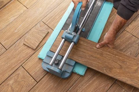 Worker placing ceramic floor tiles on adhesive surface, leveling with rubber Stock Photos