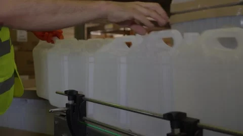 Worker Placing Empty Coolant Containers on Conveyor Line Stock Footage 336186900