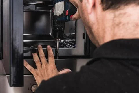 Worker placing a microwave to a kitchen cabinet Stock Photos