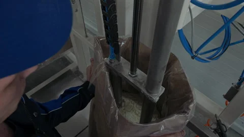 Worker is placing the open bag with flour under the modern processing machine Stock Footage 220895574