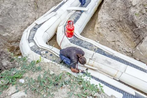 Worker is placing set of Styrofoam thermal insulation on new pipeline in tren Stock Photos