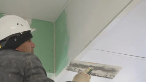 Worker plains stucco onto wall with putty knife in office Stock Footage 314647623