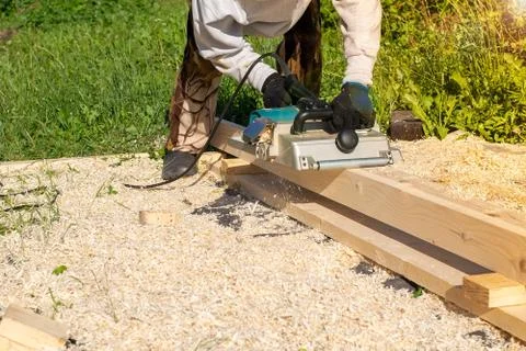 Worker planes a Board with a power tool Stock Photos