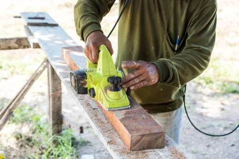Worker planing a plank of wood with a electric plane Stock-Fotos