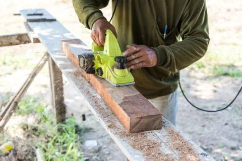 Worker planing a plank of wood with a electric plane Stock Photos