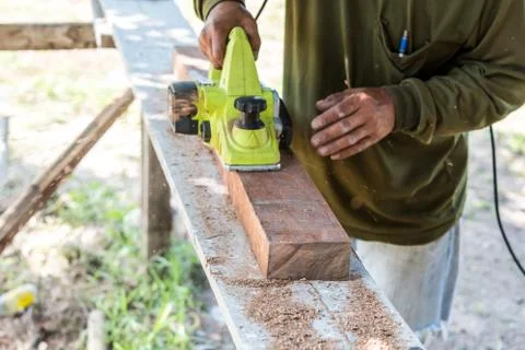 Worker planing a plank of wood with a electric plane Stock Photos