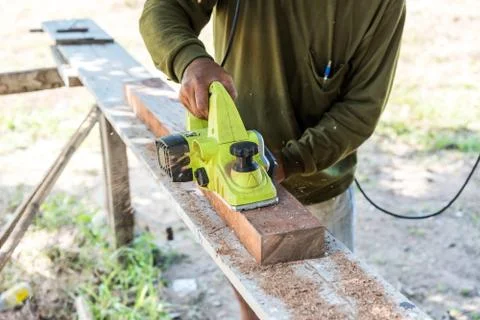 Worker planing a plank of wood with a electric plane Stock-Fotos