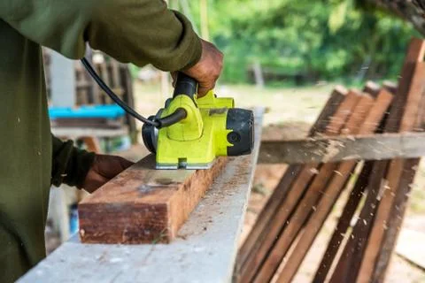 Worker planing a plank of wood with a electric plane Fotos de archivo