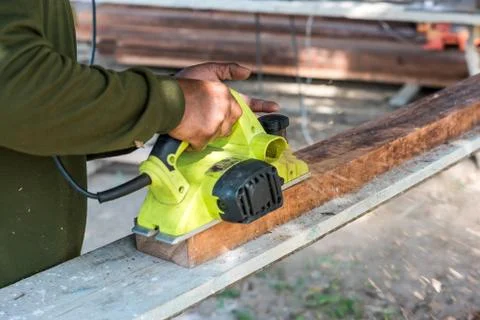Worker planing a plank of wood with a electric plane Fotos Stock