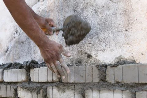 Worker plastering brick wall with putty knife at construction site Stock Photos