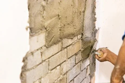 Worker plastering cement mortar on brick wall with trowel Stock Photos
