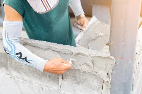 Worker plastering cement at wall for building bund oil tank in factory. Foto stock