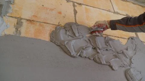 Worker plastering concrete block wall with cement mortar using trowel Stock Photos