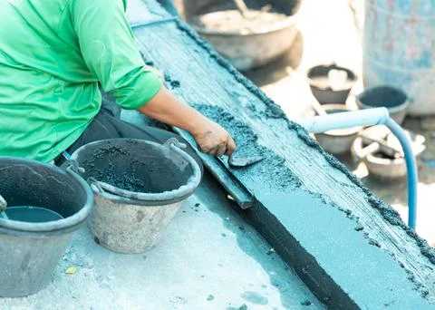 Worker plastering exposed aggregate finish on foot path Stock Photos