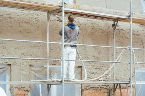 Worker plastering outer wall of newly built house Stock Photos