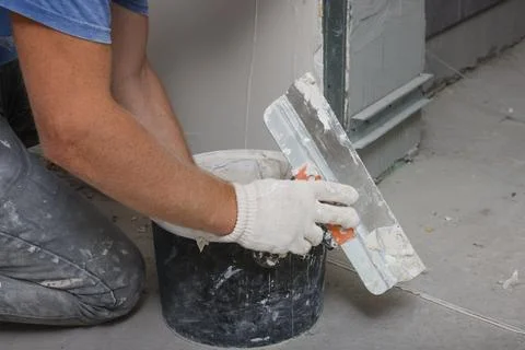 Worker plastering wall with putty knife indoors, closeup Fotos de archivo