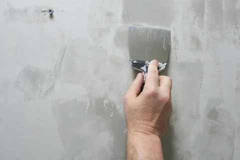 Worker plastering a wall with a spatula, close-up Stock Photos