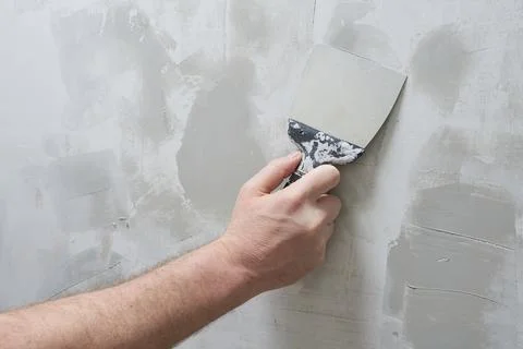 A worker is plastering a wall with a trowel. Stock Photos
