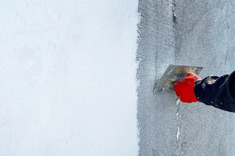 A worker plasters a wall with decorative plaster. Stock Photos