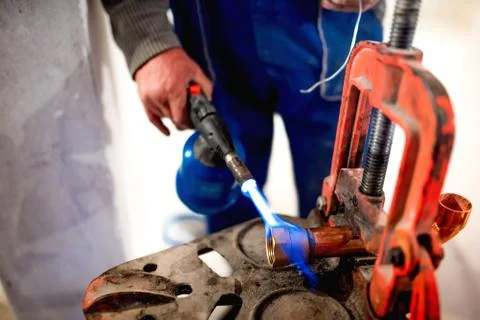 Worker, plumber using blowtorch for soldering copper fittings Stock Photos