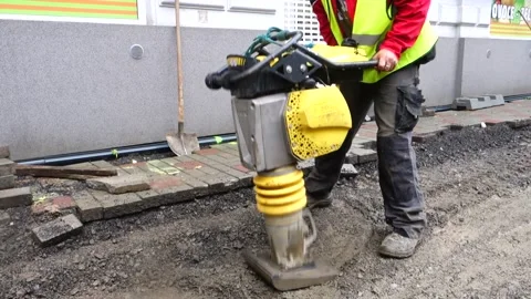 Worker with a pneumatic sand kneader, vibrating machine, on street Stock Footage 157127314