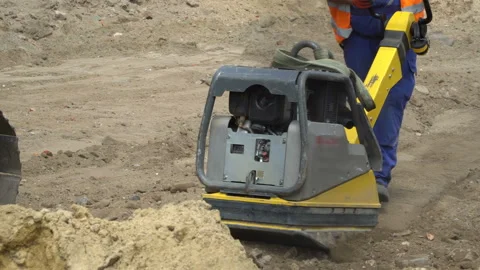 A worker with a pneumatic sand kneader, vibratory  plate,  repairs the road surf Stock Footage 113084645