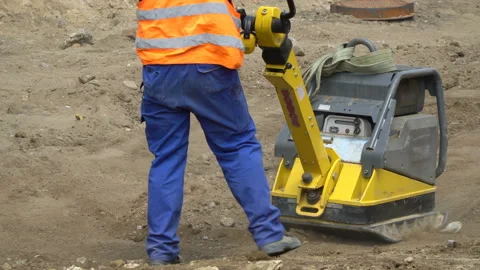 A worker with a pneumatic sand kneader, vibratory  plate,  repairs the road surf Stock-Footage 113085555
