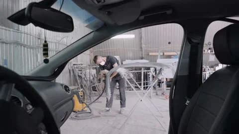 Worker polishes car bumper in workshop view from auto salon Stock Footage 134224251