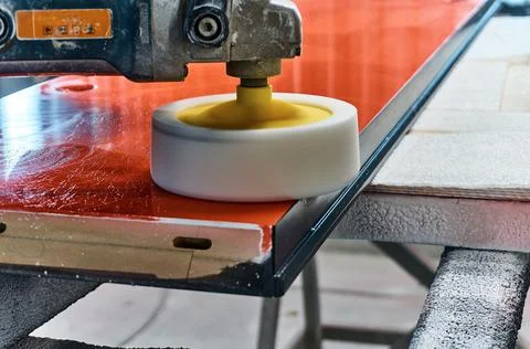 Worker polishes a red panel with a grinder. Woodworking and carpentry production Stock Photos