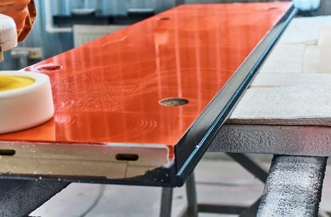 Worker polishes a red panel with a grinder. Woodworking and carpentry production Stock Photos
