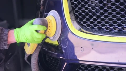 Worker polishing car bumper with orbital machine in auto body shop close-up Stock Footage 334861265
