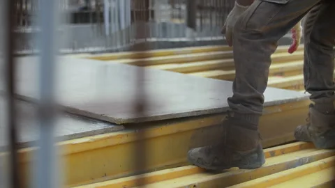 Worker positioning floor formwork panel on yellow beams Stock Footage 314235198