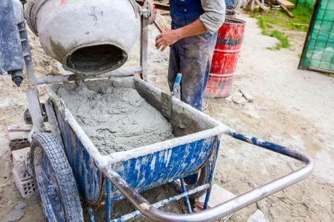 Worker is pour mortar in wheelbarrow Stock Photos