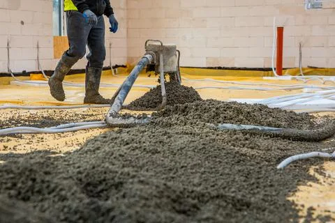Worker Pouring Concrete Over Protective Layer in Indoor Construction Site Stock Photos