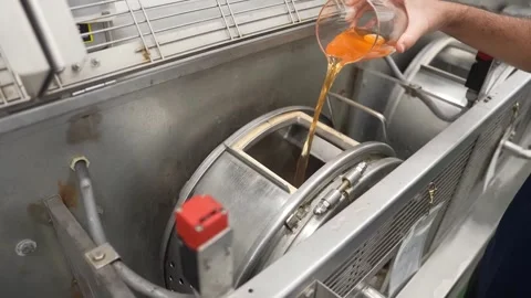 Worker pours amber dye solution into rotating tanning drum machine Vídeos de archivo 339245161
