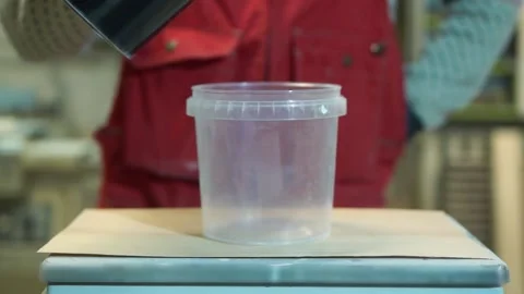 Worker pours black paint into container standing on scale Vidéo 163423241