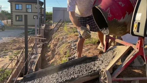 A worker pours out concrete or cement from a concrete mixer, Stock Footage 238810186