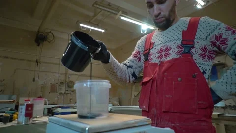 Worker pours solvent into container with  black paint standing on scale Stock Footage 163423253
