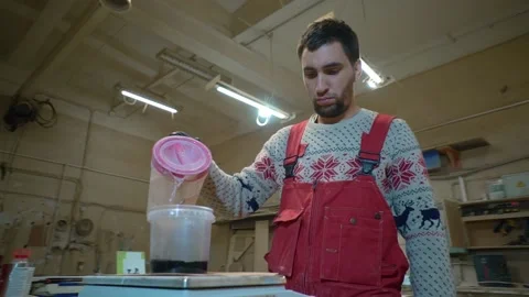 Worker pours solvent into container with  black paint standing on scale Stock-Footage 163423254